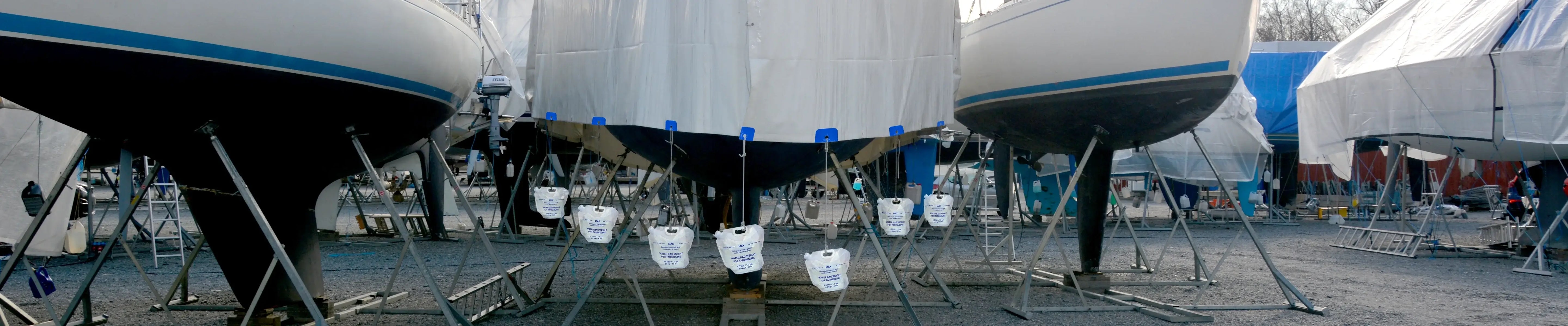 Sailboats stored on land with protective tarps for winter marine storage