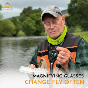 Angler inspecting a fly using magnetic fly fishing magnifier 8275 beside the river.